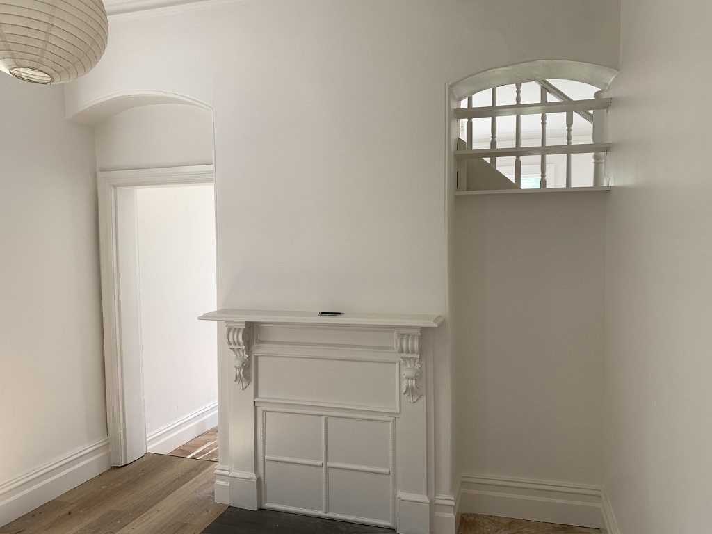 Freshly painted Victorian terrace room in Carlton showing ornate fireplace surround, cornices and arched doorway