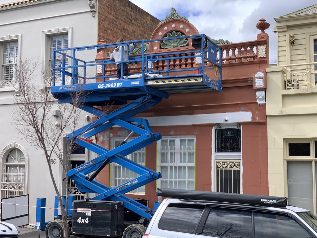 GS-2669 RT scissor lift positioned in front of 384 Drummond Street Carlton during a Melbourne City Maintenance exterior repaint — access equipment at this height must stay clear of the No Go Zone around overhead conductors
