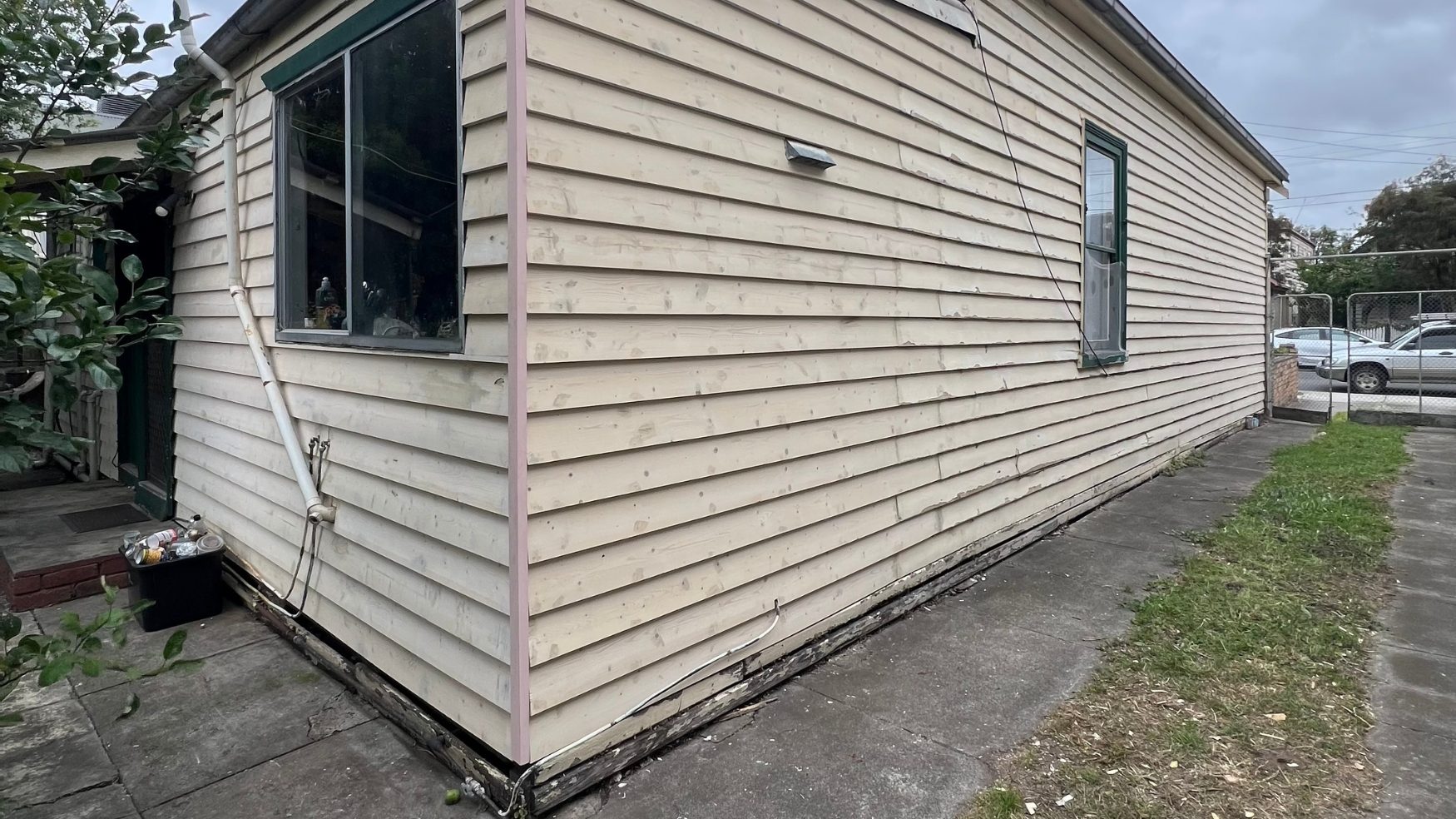 Northcote weatherboard wall sanded back to bare timber ready for painting, with rot visible along the bottom boards